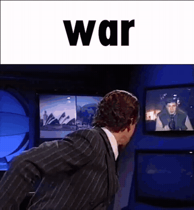 Man In Suit In Front Of TV Saying War GIF