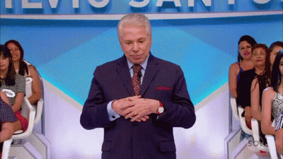 Man In Suit In Front Of TVio Santos Sign GIF