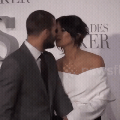 Man In Suit Kisses Woman On Cheek GIF