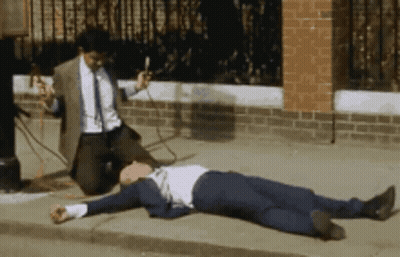 Man In Suit Kneeling Beside Man On Sidewalk GIF