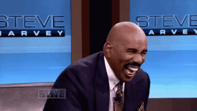 Man In Suit Laughing In Front Of Steve Harvey Sign GIF