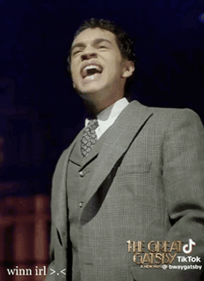 Man in Suit Laughing in Front of The Great Gatsby Sign