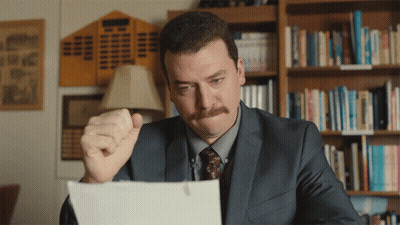 Man In Suit Looking At Paper With Fist In Air GIF