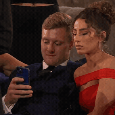Man In Suit Looking At Phone Woman In Red Dress Looking At Him GIF