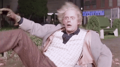 Man In Suit Lying In Park With Arms Outstretched GIF