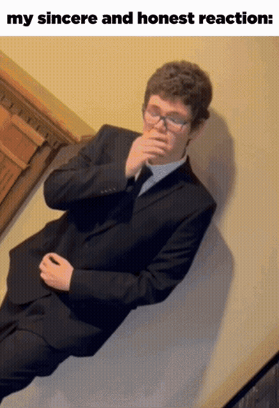 Man In Suit Lying On Wall With Hand To Mouth GIF