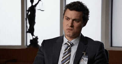 Man In Suit Making Funny Face At Justice Statue GIF