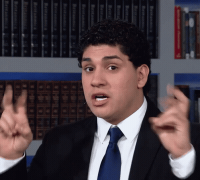 Man In Suit Making Funny Face In Front Of Bookshelf With Bible GIF