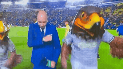 Man In Suit Next To Eagle Head Mascot GIF