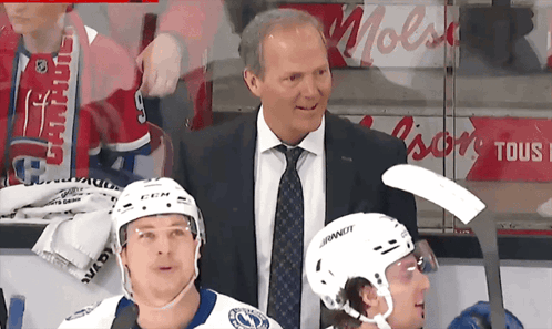 Man In Suit Next To Hockey Player Wearing Bauer Helmet GIF