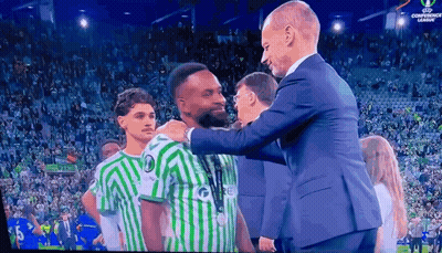 Man In Suit Next To Man In Green White Jersey Saying Re GIF