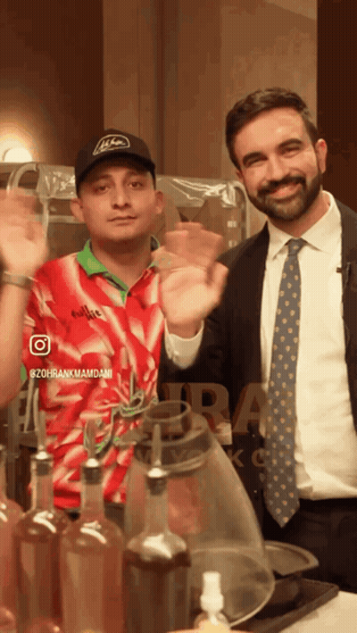 Man In Suit Next To Man In Red And White Emirates Shirt GIF