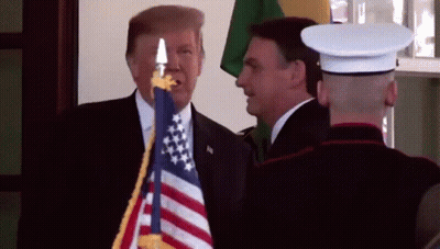 Man In Suit Next To Man In Uniform Holding American Flag GIF