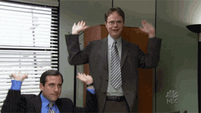 Man In Suit Next To Man With Arms Raised GIF