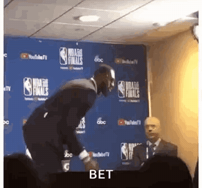 Man In Suit Next To NBA Finals Sign GIF