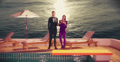 Man In Suit Next To Woman In Purple Pants GIF