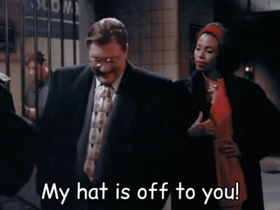 Man In Suit Next To Woman In Red Dress Saying My Hat Is Off To You GIF