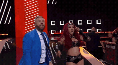 Man In Suit Next To Woman In Wrestling Costume GIF