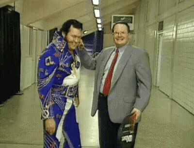 Man In Suit Next To Wrestler In Blue Outfit GIF