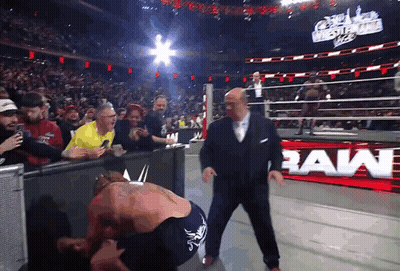 Man In Suit Next To Wrestler With Raw Sign GIF