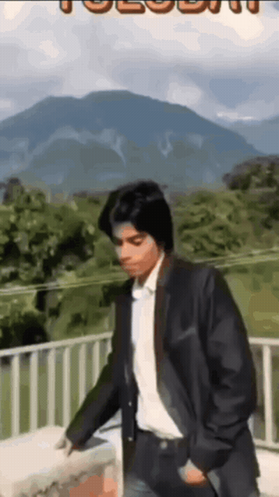 Man In Suit On Balcony With Mountains GIF