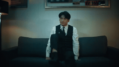 Man In Suit On Couch With Bangkok Singapore Dubai Sign GIF