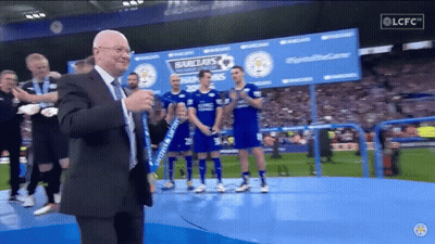 Man In Suit On Stage In Front Of Barclays Sign GIF