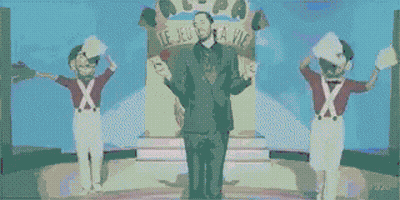 Man In Suit On Stage With Two Soldiers GIF