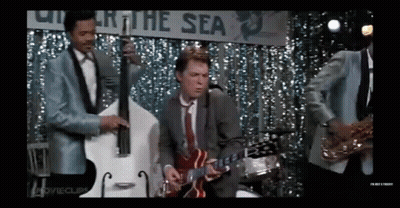 Man In Suit Playing Guitar On Stage With Band GIF