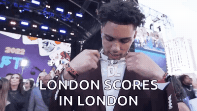 Man In Suit Putting On Chain London Scores GIF