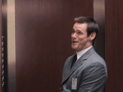 Man In Suit Raising Fists In Elevator GIF