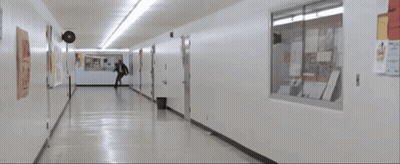 Man In Suit Running Down Hallway With Posters GIF