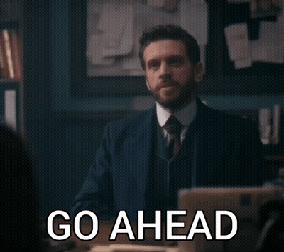Man In Suit Saying Go Ahead In Dark Room GIF