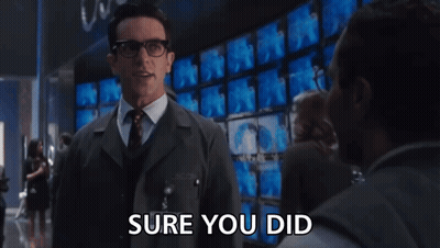Man In Suit Saying Sure You Did In Front Of Monitors GIF