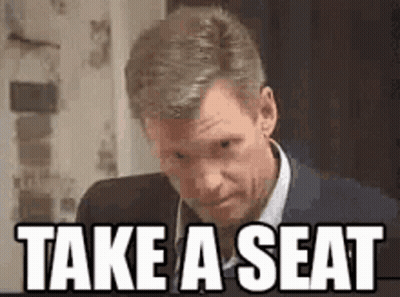 Man In Suit Saying Take A Seat GIF