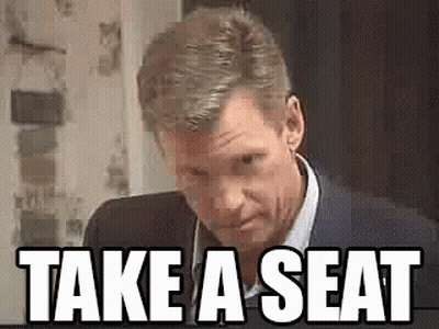 Man In Suit Saying Take A Seat GIF