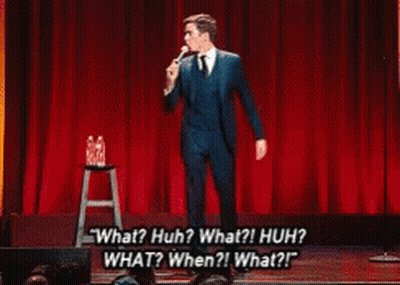 Man In Suit Saying What Huh On Stage GIF