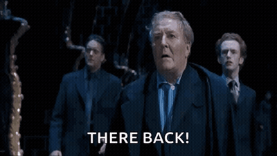Man In Suit Says There Back In Dark Room GIF