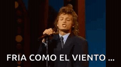 Man In Suit Singing Into Microphone On Stage GIF