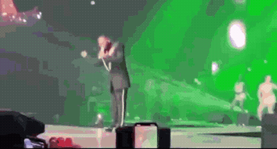 Man In Suit Singing Into Microphone On Stage GIF