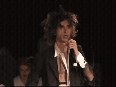 Man In Suit Singing Into Microphone On Stage GIF