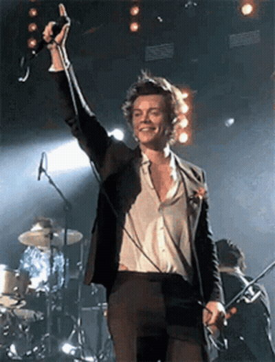Man In Suit Singing Into Microphone On Stage With Drum Set GIF
