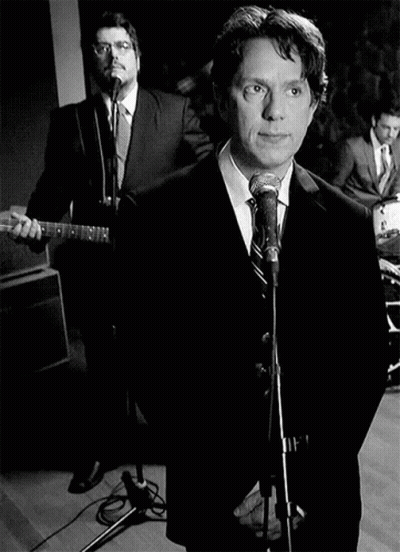 Man In Suit Singing Into Microphone With Guitarist GIF