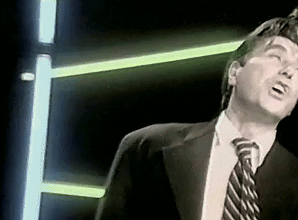 Man In Suit Singing Into Microphone With Neon Lights GIF