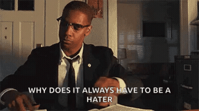Man In Suit Sitting At Desk With Book And Glasses GIF