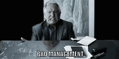Man In Suit Sitting At Desk With Broken Glass Making Funny Face GIF