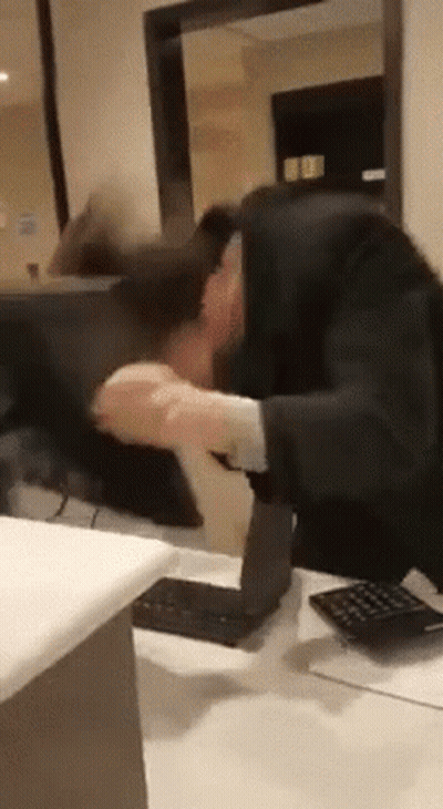 Man In Suit Sitting At Desk With Calculator And Computer GIF