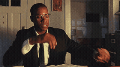 Man In Suit Sitting At Desk With Hand On Chin GIF