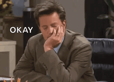 Man In Suit Sitting At Desk With Hand On Chin Saying Okay GIF