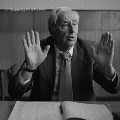 Man In Suit Sitting At Desk With Hands In Air La Guarimba Film Festival GIF